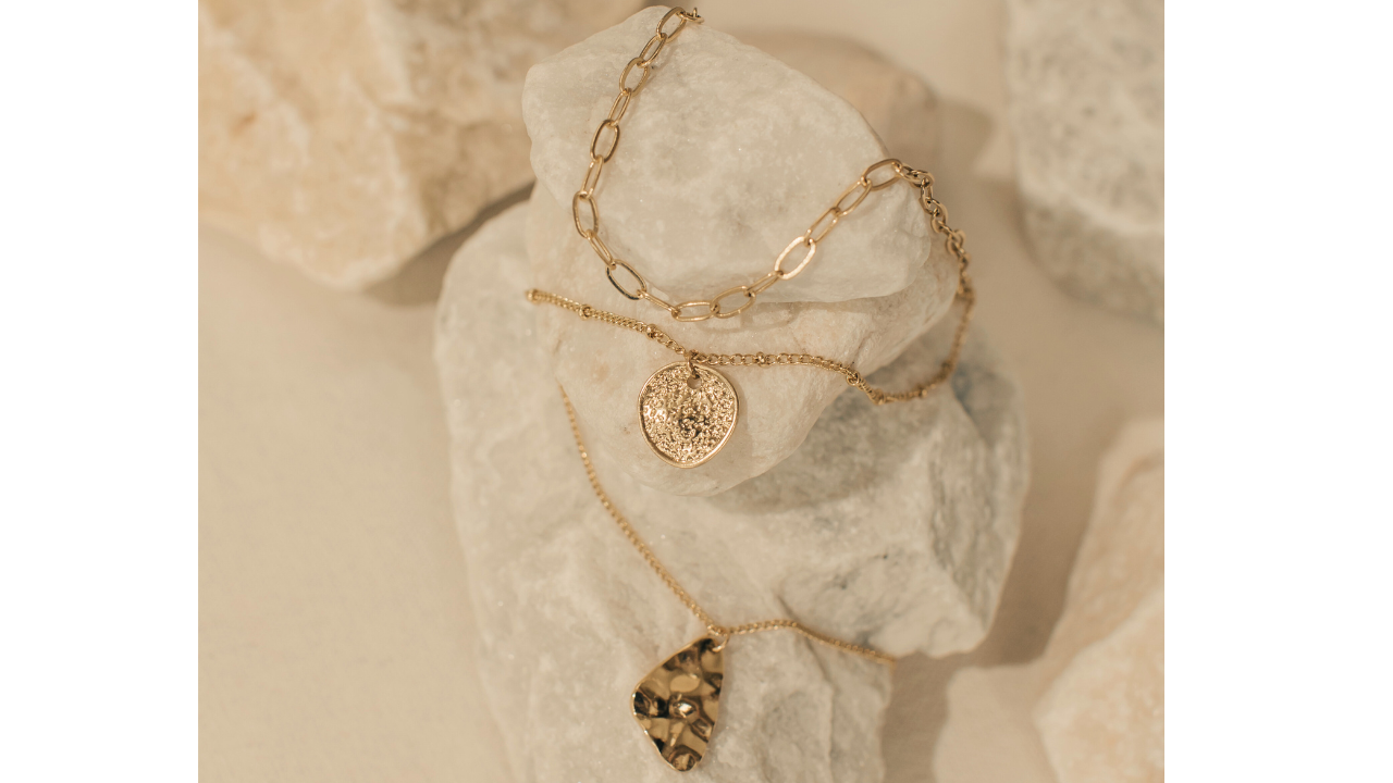 A minimalist Silver coloured earrings with small hangings and a silver chain necklace with a transparent circular pendant.