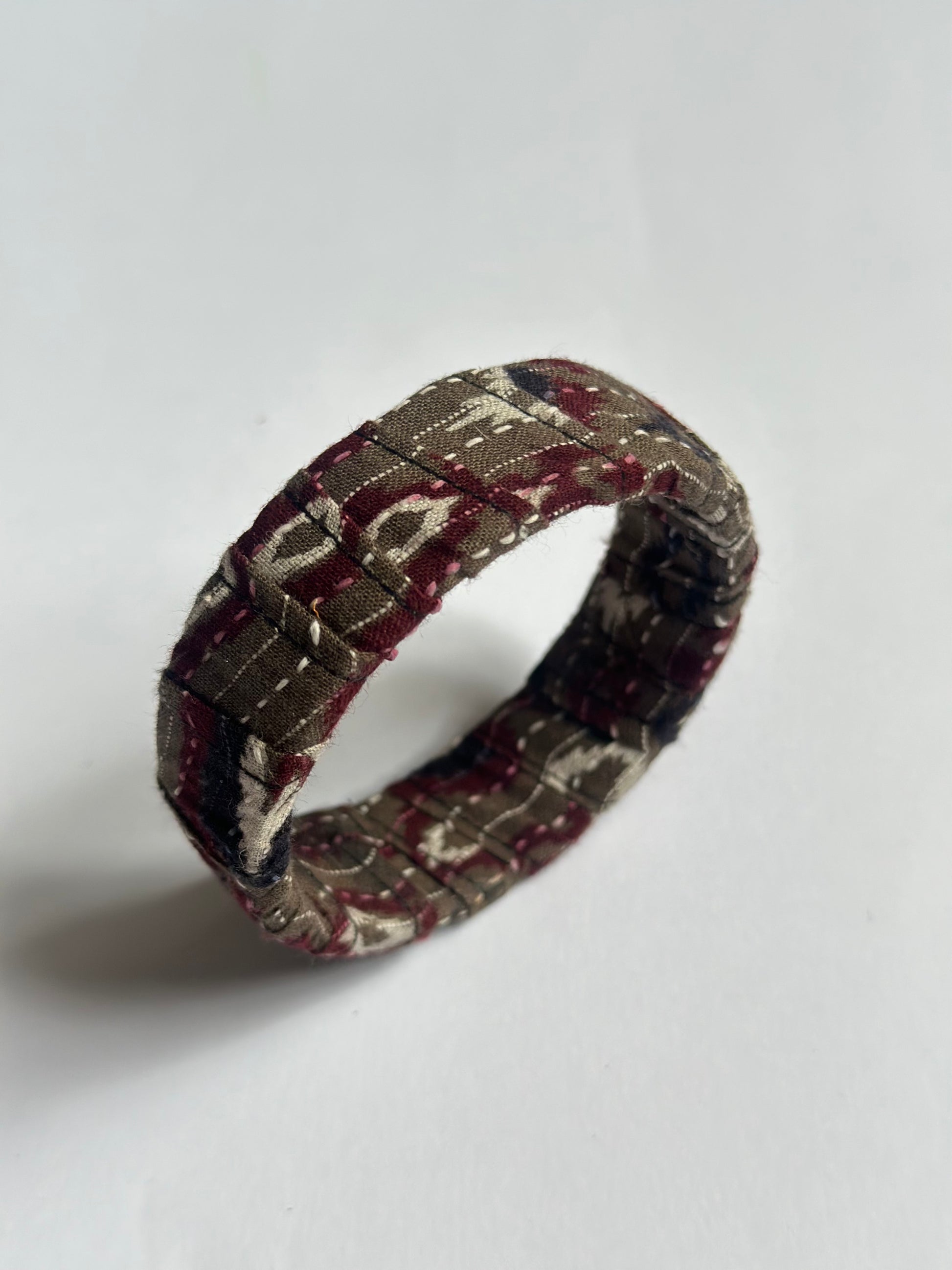 Fabric-wrapped handmade bangle with a pattern on a white background