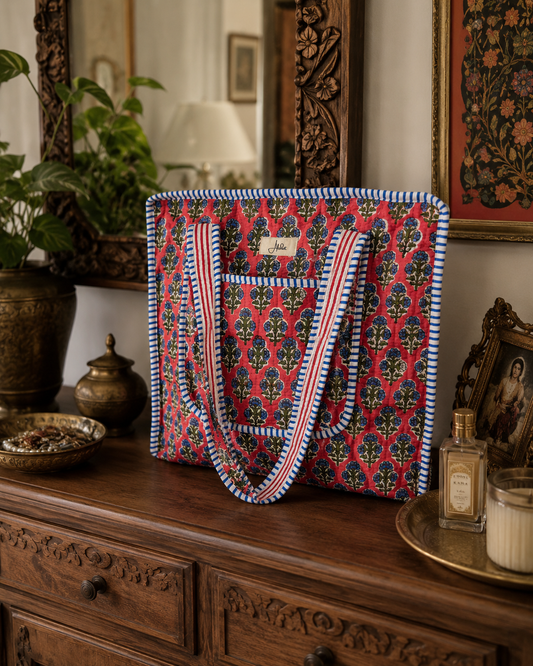 A floral-patterned quilted bag with pockets on a wooden dresser with decorative items