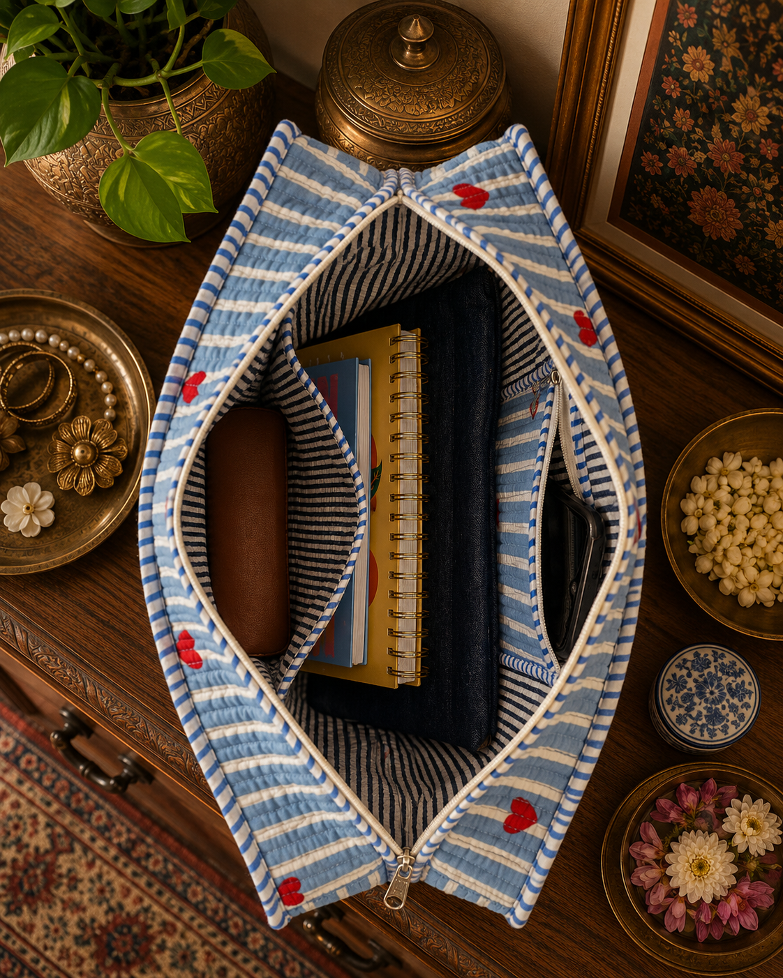 Blue and white striped fabric pouch with red heart decorations on a wooden surface with decorative items.