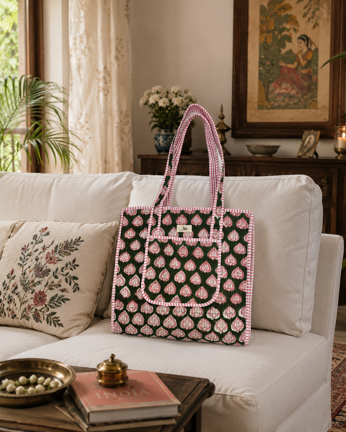 Decorative bag with a pink and dark green pattern on a white sofa in a living room setting.