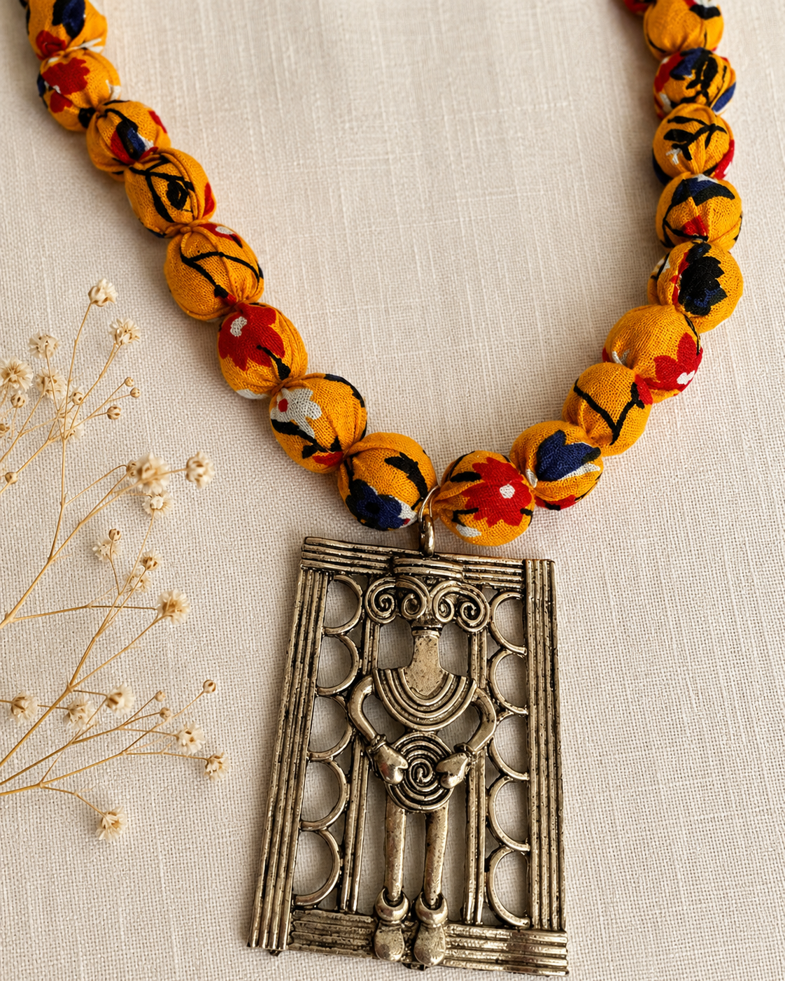 Fabric Necklace with a decorative metal pendant on a beige fabric background