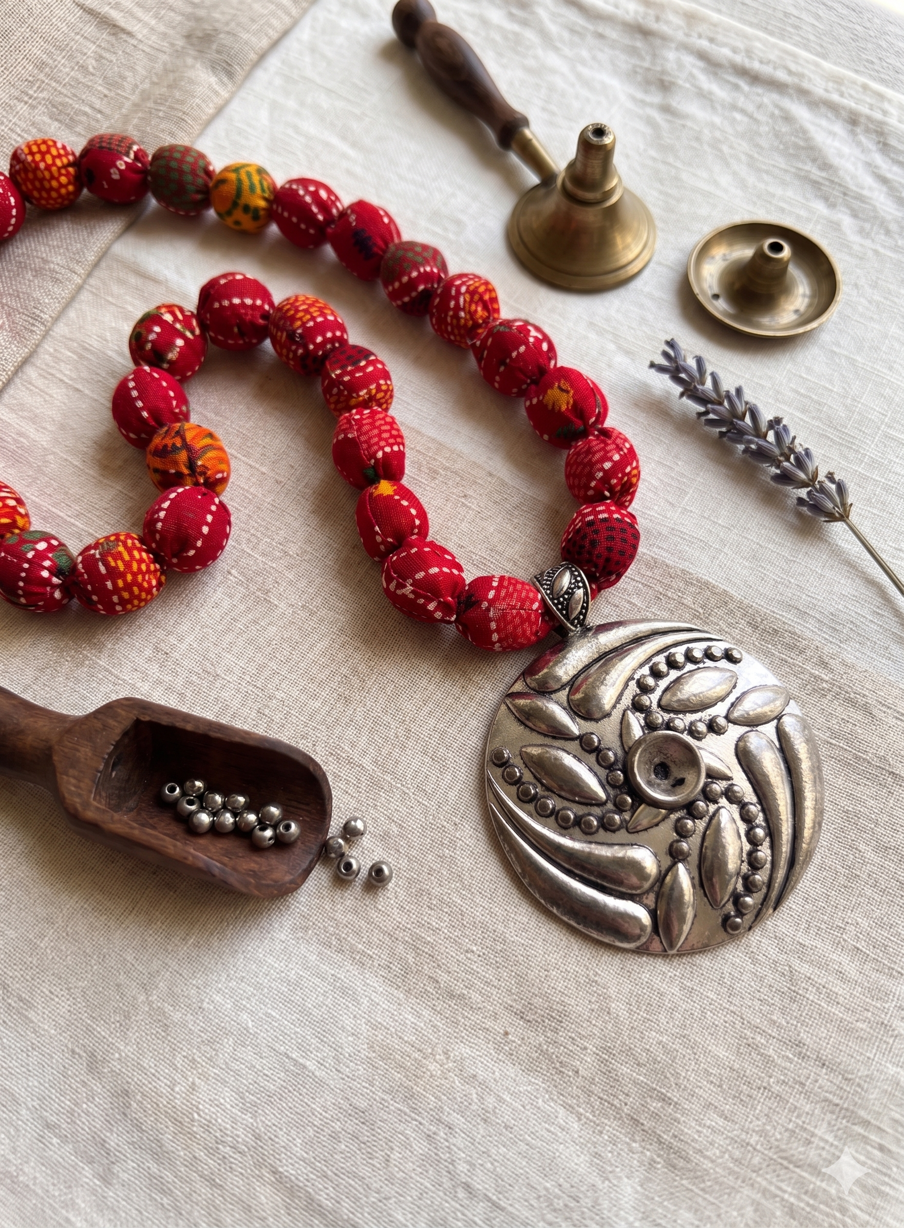 A Red fabric beaded necklace with a silver pendant on a textured surface