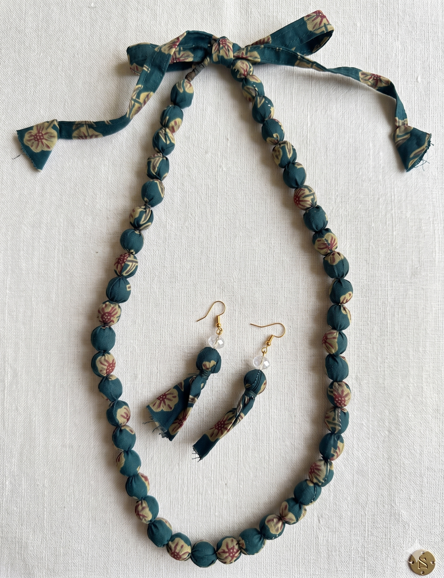 Fabric jewelry set with necklace and earrings on a light background