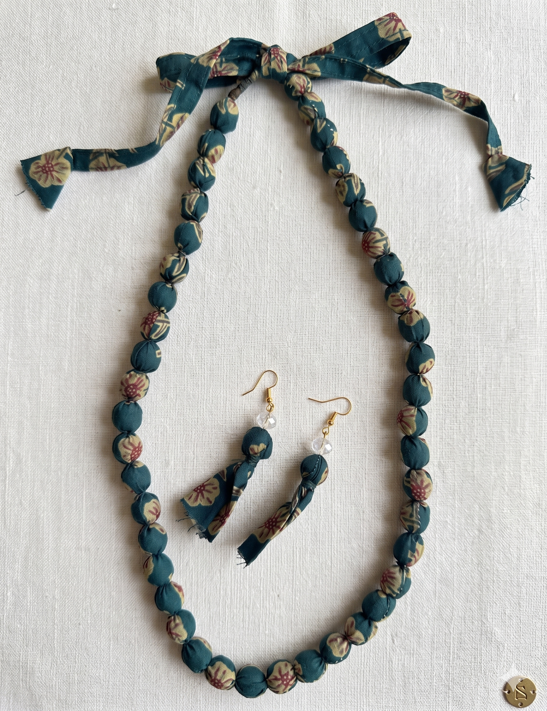 Fabric jewelry set with necklace and earrings on a light background