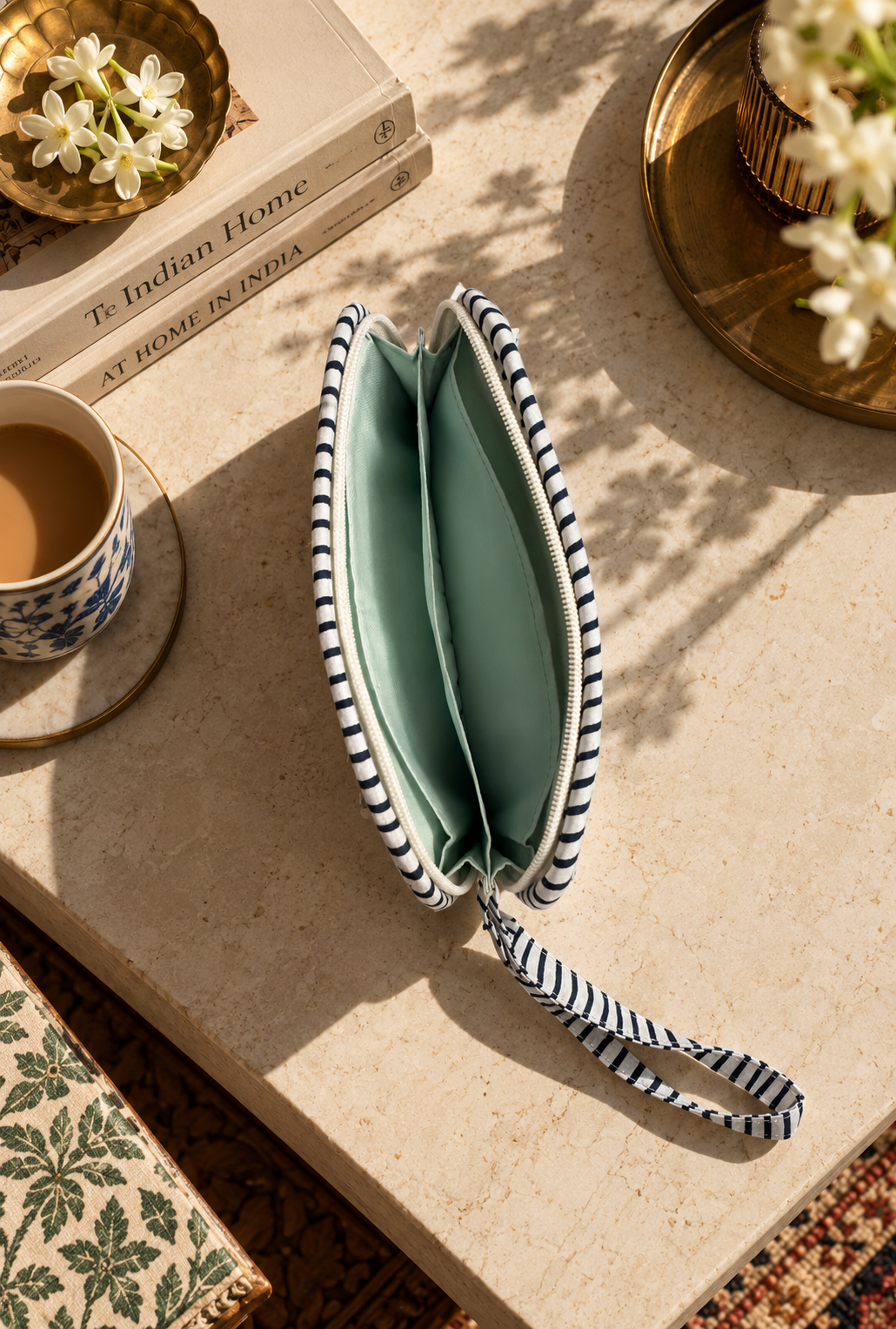 A floral-patterned quilted wallet clutch on a marble table with an open zipper showing an inner water-resistant interior
